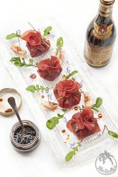 some food is laying out on a clear platter next to a bottle of wine