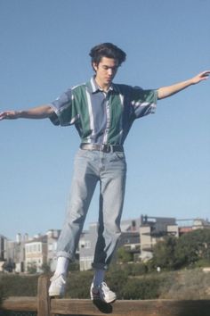 a young man riding a skateboard on top of a wooden rail with his arms outstretched