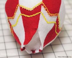 a red and white ornament sitting on top of a tiled counter next to a ruler