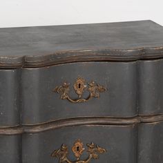 an old dresser with two drawers and ornate handles on it's sides, painted black