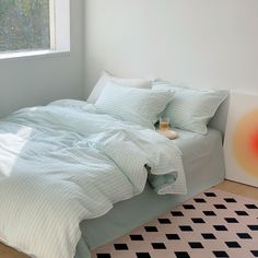 a bed sitting next to a window in a room with a checkered rug on the floor