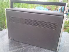 an old style radio sitting on top of a table in front of some grass and bushes