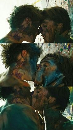 two people kissing each other with their faces covered in blue and green paint on them