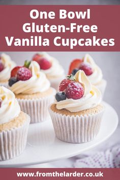 there are cupcakes with white frosting and berries on top, one bowl gluten - free vanilla cupcakes