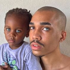 a man holding a small child in front of his face and looking at the camera