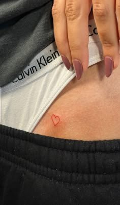 a woman's stomach with a small heart tattoo on it