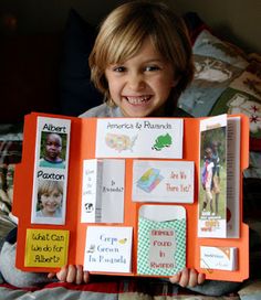 a young boy holding an orange book with pictures on it