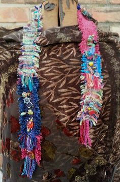 a piece of cloth with beads on it sitting on top of a wooden table next to a brick wall