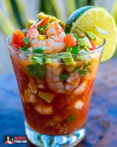 a glass filled with food and garnish sitting on top of a blue table