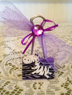 a purple ribbon is tied to a zebra keychain on a lace tablecloth