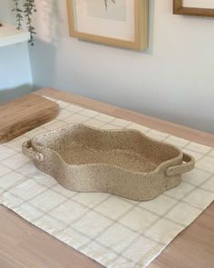 a stone bowl sitting on top of a wooden table next to a framed painting and potted plant