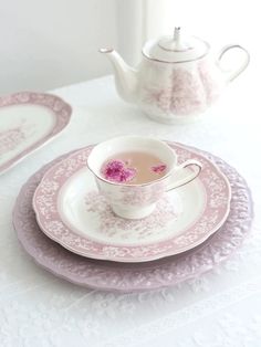 a pink and white tea set on a table