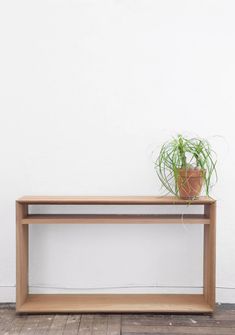 a potted plant sitting on top of a wooden shelf next to a white wall