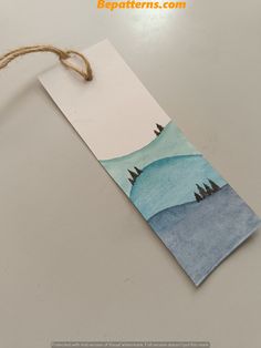 a paper tag with trees on it hanging from a string attached to a table top