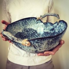 a person holding a bowl in their hands with something on it that is blue and white