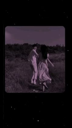 two people are walking in the grass at night