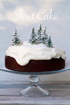 a cake with white frosting and trees on top is sitting on a glass platter