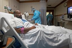 a man laying in a hospital bed next to another person wearing scrubs and medical equipment