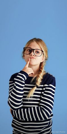 a young woman wearing glasses is posing for the camera with her hand on her chin