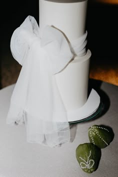 a white wedding cake on a table with two green shoes next to it and a bow