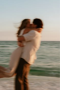 a man and woman embracing on the beach