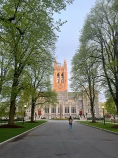 a person walking down the middle of a road in front of a building with trees