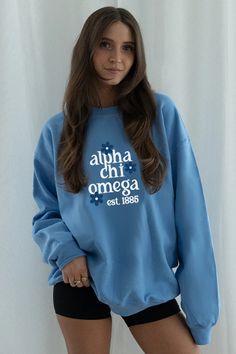 a woman wearing a blue sweatshirt with the words aloha chi omega on it