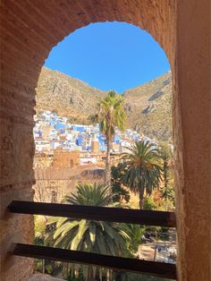 the view from inside an arch looking out at a town and mountains in the distance