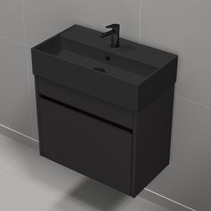 a black bathroom sink sitting on top of a tiled floor next to a wall mounted faucet