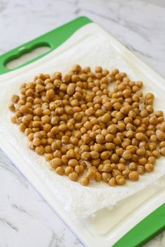 some chickpeas are sitting on a white and green cutting board, ready to be cooked