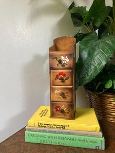 three books stacked on top of each other next to a potted plant