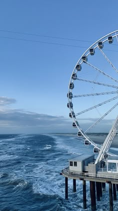 a ferris wheel sitting on top of a pier next to the ocean