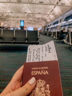 someone is holding their passport in front of an empty seat area at the airport terminal