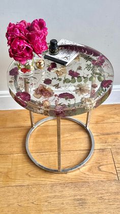 a glass table with flowers on it and a book sitting on top of the table