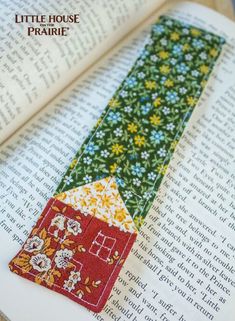 a bookmark made out of an old book with flowers and a house on it