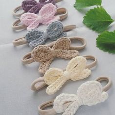 several crocheted hair clips are lined up on a white table with green leaves