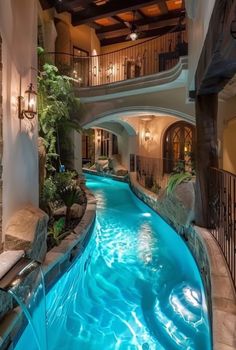 an indoor swimming pool with waterfall in the middle and stairs leading up to the second floor