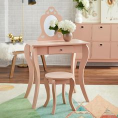 a pink desk with a mirror and flower vase on it