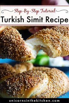 sesame seed bagels are being held up by someone's hands over a blue plate