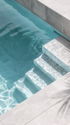 an empty swimming pool with steps leading up to the water's edge and palm tree next to it