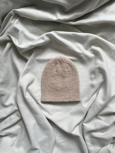 a white beanie laying on top of a bed