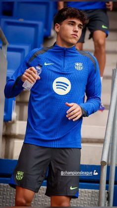 a man in blue shirt and black shorts standing next to stairs