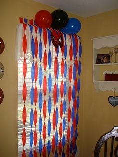 balloons and streamers are hanging from the curtain in this room with yellow walls, white shelves, and red and blue striped curtains