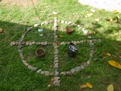 a peace sign made out of rocks and stones in the grass with small pots around it