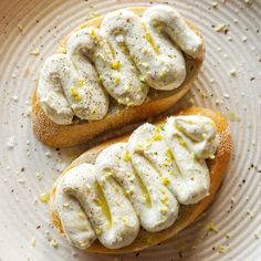 two pieces of bread topped with whipped cream and lemon zest on a white plate