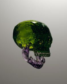 a green diamond in the shape of a skull on a gray background with water droplets