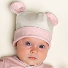 a baby wearing a pink and white bear hat on top of it's head