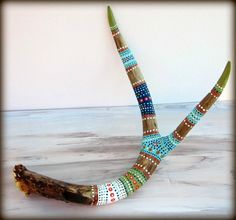 a wooden branch with beads on it sitting on top of a wood floor next to a white wall