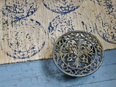 an ornate doorknob on the floor in front of a blue painted wall and rug