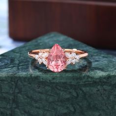 a pink diamond ring sitting on top of a green marble counter